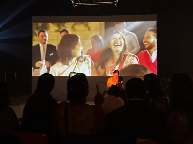 Guests silhouetted against a big lit screen showing photos at a venue
